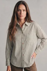 Camisa de corte oversize con estampado de rayas verticales, cuello clásico, cierre frontal con botones y bolsillo en el pecho. Presenta mangas largas con puños abotonados y dobladillo redondeado.