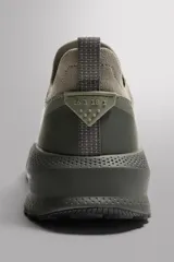 Zapatilla de running color verde oliva, con parte superior de tejido de punto transpirable y refuerzos en puntera y talón. Cuenta con entresuela con tecnología de amortiguación, suela de goma y tirador en el talón.