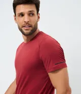 Remera deportiva de hombre en color rojo oscuro, con mangas cortas, cuello redondo y detalle de líneas negras en la manga. Confeccionada en poliéster con tecnología dry fit.
