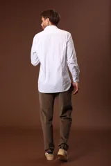 Camisa blanca de manga larga con cuello clásico y cierre frontal con botones.