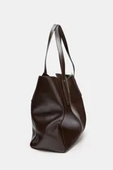 Bolso tipo shopper de gran tamaño, color marrón oscuro, con acabado brillante y doble asa de hombro con pespuntes decorativos. Cuenta con cierre mediante botón imantado y bolsillo interior con cremallera.