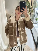 Campera tipo gamulán de cuero color marrón con interior y detalles de corderito en color crema. Presenta cierre frontal con botones, bolsillos frontales y diseño de paneles.