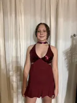 Vestido corto plateado con lentejuelas, escote en V y cut-outs laterales bajo el busto. Breteles finos que se cruzan en la espalda y atan atrás. Volado en el ruedo.