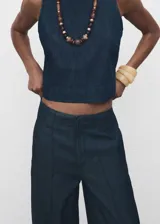 Pantalón de tiro alto con diseño wide leg, confeccionado en tejido de algodón y lyocell estilo denim. Presenta costuras verticales decorativas, bolsillos laterales y cierre oculto con botón, gancho y cremallera.