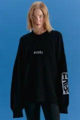 Sweater oversize de tejido de punto grueso en color negro, con cuello redondo y diseño de estampado gráfico en el pecho y en una de las mangas. Presenta un acabado desgastado que le otorga un estilo vintage.