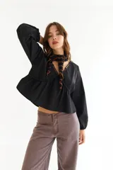 Blusa blanca de algodón con diseño de escote en V, mangas largas abullonadas y detalle de frunces en el frente y la espalda.