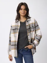 Sobrecamisa de corte holgado con estampado de cuadros en tonos gris, blanco y mostaza. Presenta cuello clásico, cierre frontal con botones, mangas largas con puños abotonados y bolsillos frontales con solapa.