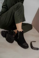 Bota corta de gamuza negra con punta cuadrada, suela track dentada y cierre lateral. Incluye una tira desmontable con tachas metálicas.