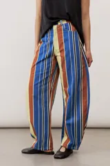 Pantalón de corte ancho y relajado con rayas verticales multicolor en tonos azul, marrón, amarillo, blanco y negro.