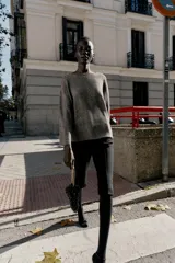 Jersey de punto color marrón oscuro con lentejuelas plateadas, cuello barco y manga larga acampanada.