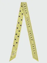 Pañuelo tipo bandana de seda, color amarillo con estampado gráfico y letras en negro. Diseño cuadrado con bordes definidos.