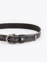 Cinturón de cuero vacuno con efecto gastado, hebilla metálica y aplique decorativo en forma de corazón.