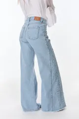 Pantalón de jean estilo wide leg en color celeste claro, con diseño de costuras verticales a lo largo de las piernas y ruedo deshilachado. Cuenta con etiqueta de cuero de la marca Petra en la parte posterior.