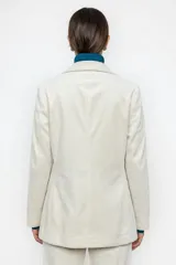 Blazer de pana color crudo, con solapas clásicas, cierre frontal de un botón y bolsillos laterales con solapa.