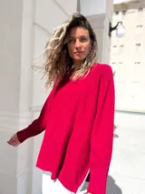 Sweater de punto color bordó, con diseño oversize, cuello redondo, mangas largas con puños acanalados y costura central vertical. Presenta un corte asimétrico con aberturas laterales en el ruedo.