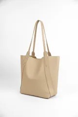 Bolso tipo tote de diseño minimalista, confeccionado en material texturizado color beige, con doble asa larga para llevar al hombro y costuras reforzadas en los laterales.