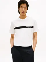 Remera de algodón blanco con cuello redondo y manga corta. Presenta una banda horizontal negra en el pecho con el nombre de la marca estampado en tipografía cursiva blanca.