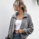 Campera corta de textura peluda tipo polar, color gris, con cierre frontal, cuello alto y elástico ajustable en la cintura.