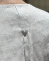 Blusa corta de lino natural color blanco, con mangas acampanadas y bordados a mano inspirados en motivos marinos como anclas, soles y estrellas de mar.