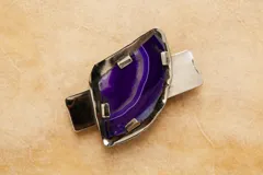 Hebilla para el cabello con piedra de ágata natural en color violeta engarzada en una base metálica plateada.