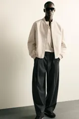 Pantalón de corte balloon fit confeccionado en tejido con viscosa. Presenta cintura ajustable con cinturón integrado, pliegues frontales, bolsillos laterales y bolsillos traseros de doble vivo. Cierre frontal con cremallera y botón.