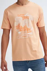 Camiseta de manga corta color salmón con estampado frontal estilo retro con temática de surf.