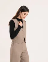 Chaleco de vestir gris oscuro con textura tipo tweed, escote en V y botones frontales. Corte levemente entallado y largo a la cintura.