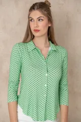 Camisa verde con lunares negros, de manga larga y cuello camisero.