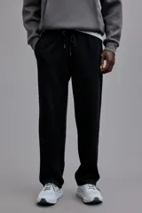 Pantalón de jogging negro de punto pesado, corte recto y calce estándar. Posee cintura elástica con cordón ajustable y bolsillos laterales insertados.