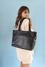 Cartera tipo shopper de cuero marrón texturado, con doble asa de hombro y un bolsillo frontal amplio con cierre de imán.