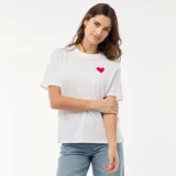 Camiseta de manga corta color blanco con cuello redondo y pequeño corazón rojo estampado en el pecho.