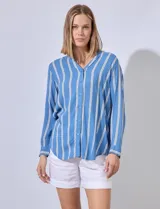 Camisa celeste con rayas verticales blancas, de corte clásico, cuello a la base, escote en V y cierre frontal con botones.