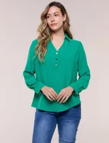 Blusa verde de calce holgado y caída fluida, confeccionada en tejido tipo crepé. Cuenta con cuello camisero con solapa, escote en V y cierre parcial al frente con tres botones metálicos. Las mangas son largas con puños abotonados.