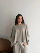 Conjunto de dos piezas de lanilla en color gris melange, compuesto por una blusa de corte amplio con mangas murciélago y escote bote, y un pantalón recto con bolsillos laterales.
