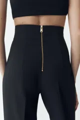 Pantalón de vestir color crudo, de tiro alto y pierna acampanada.