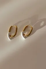 Aros de acero quirúrgico dorado con argolla rectangular y dije colgante en forma de corazón blanco de cerámica.
