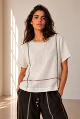 Blusa de lino color beige, de manga corta y cuello redondo, con detalles de bordados geométricos en contraste.