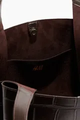 Bolso tote de mano, color marrón oscuro o negro, con textura de cocodrilo en charol. Presenta dos asas superiores fijas y un diseño amplio y estructurado.