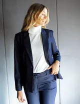 Blazer de tencel color azul marino con cuello de solapa y cierre frontal de un solo botón. Presenta bolsillos delanteros simulados con detalle de vivo trenzado y un diseño estructurado de calce entallado.