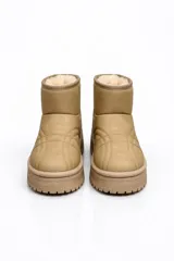 Pantubota de caña corta en color beige, con interior forrado en piel sintética. Presenta costuras decorativas en el empeine y una suela de plataforma dentada en tono a juego.