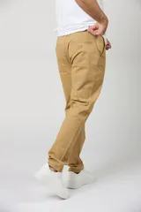 Pantalón chino de gabardina color camel, de corte recto, con bolsillos laterales y traseros, y cierre frontal con botón y cremallera.