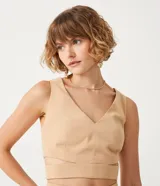 Blusa corta color beige con escote en pico y tirantes anchos. Presenta un recorte en la cintura.