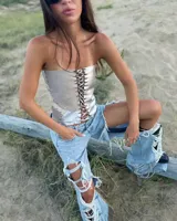 Corset de cuero plateado metalizado, con diseño strapless, cordones cruzados al frente y detalles de tachas.