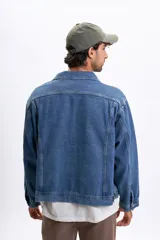 Campera de jean de hombre, color azul claro lavado, con cuello camisero, botones frontales y bolsillos con tapa en el pecho. Presenta un calce holgado.