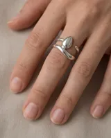 Anillo de acero quirúrgico plateado, de diseño abierto y ajustable, con detalle de gota en el frente.
