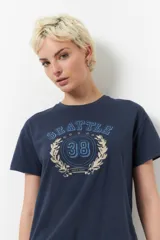 Remera de manga corta color azul marino con estampa frontal estilo universitario que incluye el texto Seattle, el número 38 y una corona de laureles.