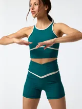 Conjunto deportivo verde oscuro compuesto por un top sin mangas con ribetes en contraste y un short de tiro alto con cintura cruzada.