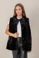 Chaleco largo de gamuza sintética color negro, con interior de piel sintética (faux fur) y cierre frontal con botones. Presenta bolsillos frontales amplios y diseño reversible.