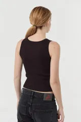 Musculosa blanca de morley de algodón peruano, de calce fitted y escote en "U". Presenta un bordado marcario a tono en el frente de la prenda.