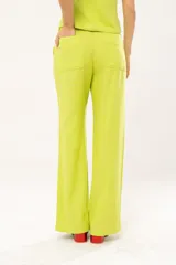 Pantalón verde lima de lino imperial con lurex, tiro medio, corte palazzo, bolsillos delanteros y traseros, cierre frontal con cremallera y botón.